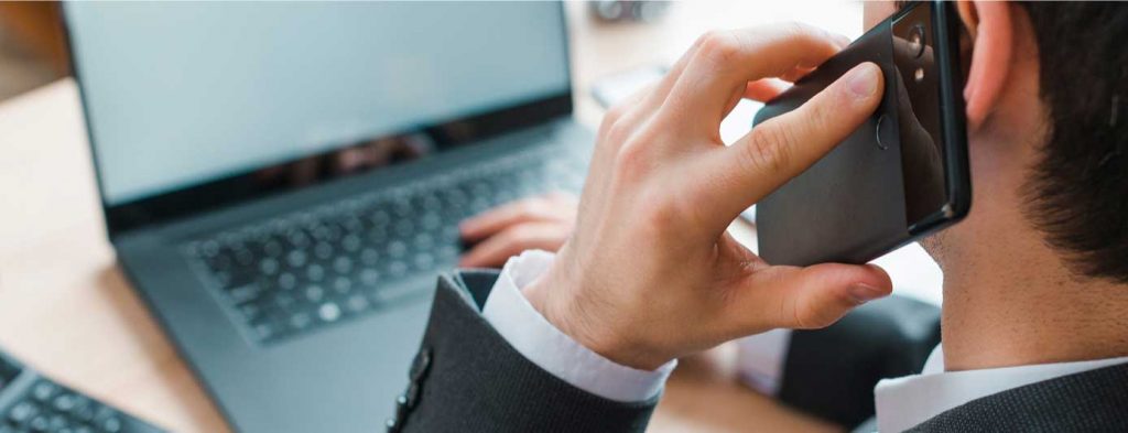Contacto Abogado - Abogado llamando por teléfono mientras ve su computadora.